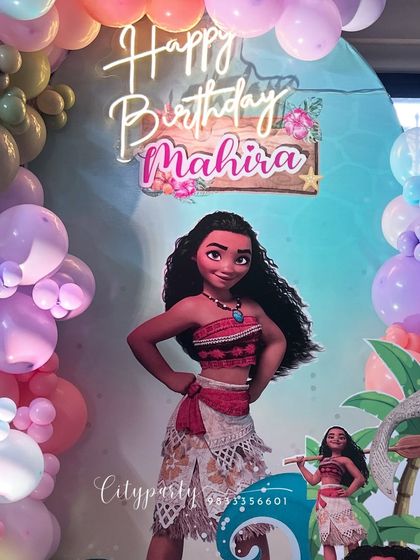 A close-up of the Moana backdrop, featuring a personalized 'Happy Birthday' sign and neon lighting.