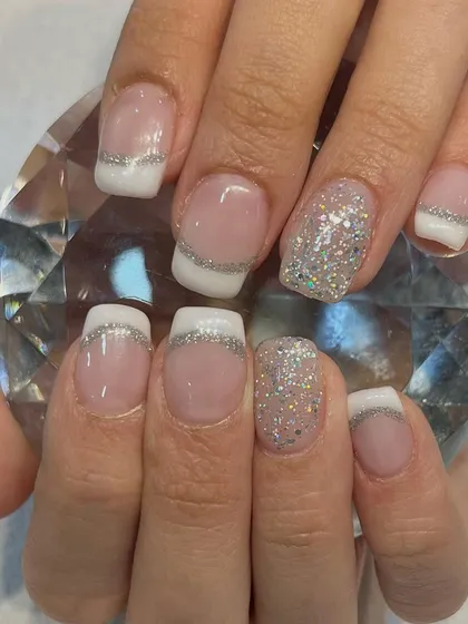A close-up of one of our favorite designs, the glitter French manicure. This elegant style uses gel polish and extensions for a flawless finish, perfect for weddings, parties, or any special occasion.