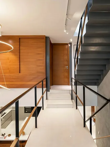 A view from the mezzanine bridge in the 'SOL' residence, looking down into the double-height living space. This image highlights the home's verticality and the interplay of different levels, connected by the sleek, minimalist staircase.