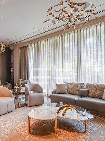 In this living room, elegant grey furnishings, gold-accented marble, and artistic light fixtures create a sophisticated atmosphere. Floor-to-ceiling windows bring in natural light, enhancing the room’s chic and airy minimalist vibe.