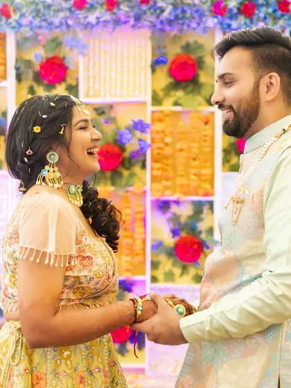 A sweet, laughing moment between the couple. The bride's makeup is natural and glowing, perfect for a daytime Haldi event.