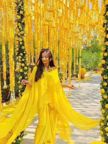 A bride enjoying her Haldi or Mehendi function in a stunning walkway decorated with hanging marigold strings. This kind of immersive decor creates fantastic photo opportunities.