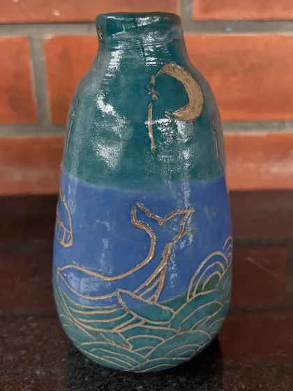 This beautiful vase with a whale and wave design was hand-carved and painted by a young student. It shows how sgraffito techniques can be used to tell a story on clay.