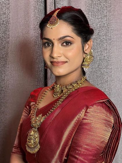 A portrait of grace. Reva looks stunning in this traditional temple jewellery set, with the antique gold finish beautifully complementing her red saree.