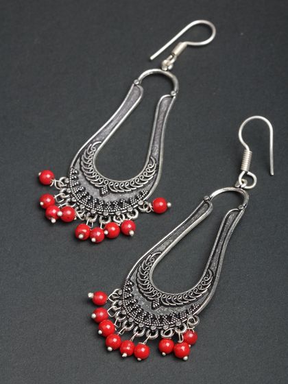 These long, U-shaped oxidized silver earrings with red beads offer a modern, geometric take on traditional designs.