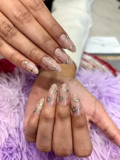 These long, almond-shaped extensions feature a sheer nude base adorned with 3D star embellishments and delicate silver studs. A celestial-inspired look that is truly out of this world.