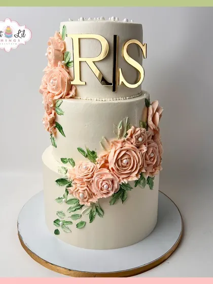 A beautiful two-tiered cake with a cascade of soft peach sugar flowers and a custom "RS" monogram.