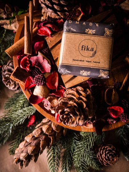 This is your official notice that the winter season soaps are coming. A single handcrafted soap bar, wrapped in black paper with my fika logo, sits in a bowl of festive potpourri, hinting at the cozy scents to come.