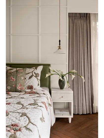 Another view of the guest bedroom, highlighting the paneled wall and the soft, natural light from the window. The room is designed to be a warm and inviting sanctuary for guests.