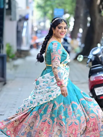 A joyful, twirling shot of Preethi at her daughter's naming ceremony. Her unique printed lehenga is paired with fresh, bright makeup and a lovely braided hairstyle.