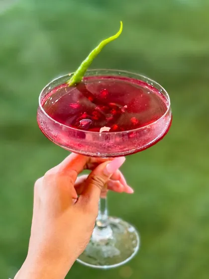 This is my Pomegranate Kulukki Slush, a vibrant and flavourful mocktail. It has the perfect balance of sweet and tangy, with a spicy kick from the green chili garnish, making it an exciting drink choice.