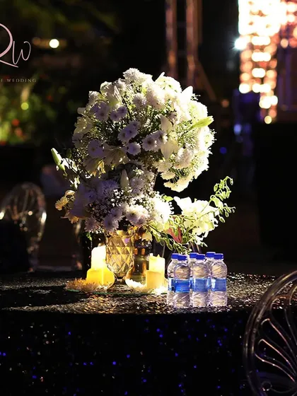 A simple yet elegant table setup with a white floral centerpiece and candles, perfect for an intimate cocktail dinner.