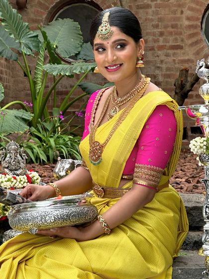 A beautiful shot of a client in a yellow Kanchivaram with a pink blouse, seated for a pooja ceremony.