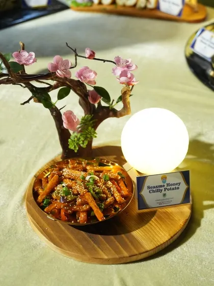 An artfully presented bowl of Sesame Honey Chilly Potato. This dish from our Asian menu is the perfect balance of sweet, spicy, and crispy, making it a popular choice for starters.