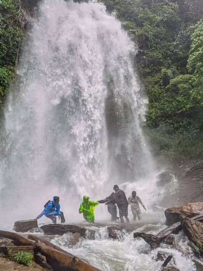 A group of trekkers carefully making their way across the rocks at the base of Hidlumane Falls.