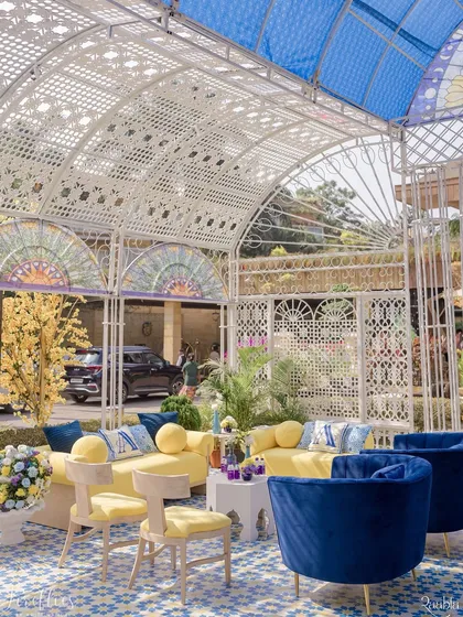 A beautiful glasshouse seating area for the Haldi. The combination of yellow sofas, royal blue armchairs, and a patterned floor created a vibrant and stylish space for guests to relax.