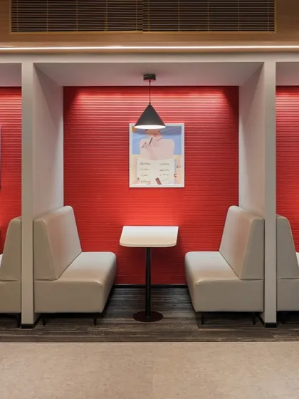 Diner-style booths in a breakout area, with a bold red accent wall. These provide semi-private spaces for employees to eat, work, or chat.