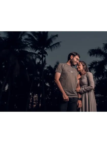 A low-light photo of Mayank and Riddhi against a backdrop of palm trees. Night and twilight couple portraits have a very intimate and cinematic quality.