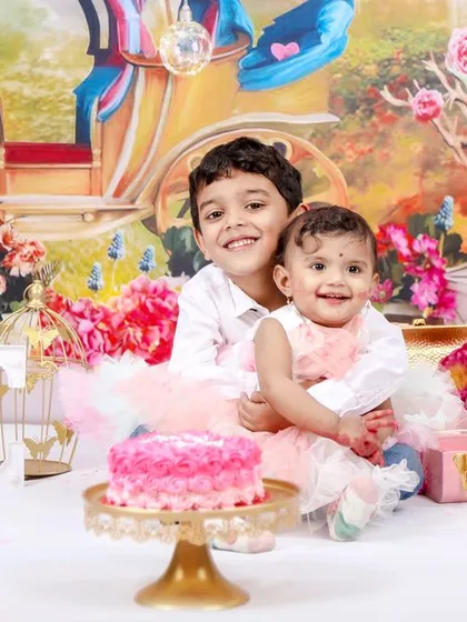 The older brother joins in the first birthday fun! This photo captures a sweet moment between siblings during a princess-themed cake smash session.