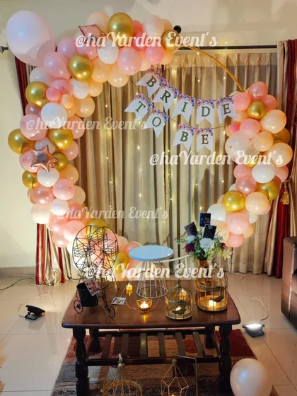 A 'Bride to Be' celebration with a beautiful balloon ring in pastel pink and gold. The fairy lights and props create a dreamy atmosphere for the bride.