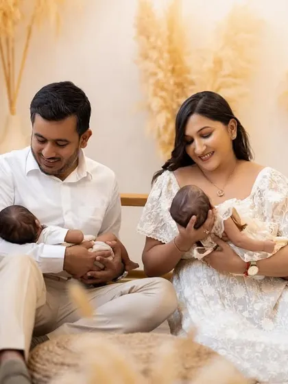 The joy of parenthood, doubled. This shot captures the happy smiles of the new parents as they each hold one of their twin babies. It's a beautiful memory from their twin newborn photoshoot.