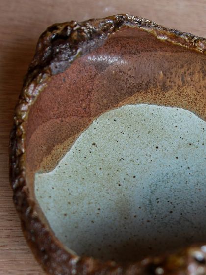 A close up of the layered glazes on a boat shaped tray, showing the beautiful, painterly effect achieved through experimentation.