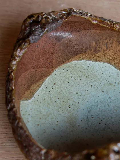 A close-up of the interior of a textured bowl, showing the beautiful color variations from the layered glazes. Each piece is a small work of art.