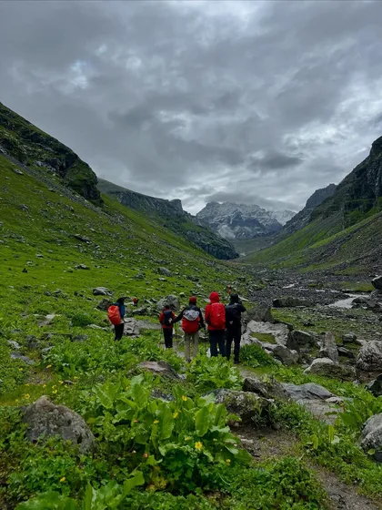 A group of trekkers making their way through the lush green lower valleys of the Hampta Pass.