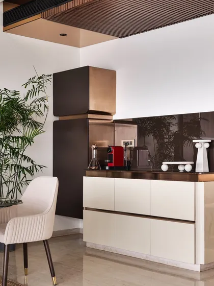 We designed this dedicated coffee bar with sleek, cream-colored cabinetry and a copper-clad accent. It’s a stylish and functional space that resembles a shiny coffee bean, ready to be brewed.