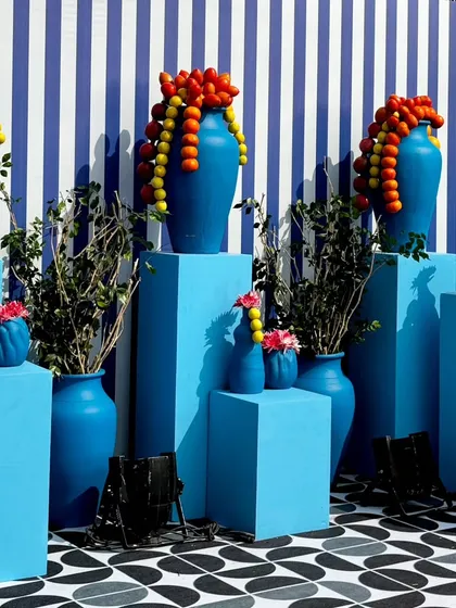 A striking arrangement of blue vases on pedestals of varying heights. The cascading garlands of lemons and pomegranates add a pop of color and a touch of the unexpected.