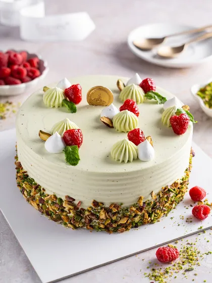 The full Pistachio Raspberry Cake, a study in subtle beauty. The smooth mascarpone buttercream is decorated with fresh raspberries and crushed pistachios, a popular choice for those who love sophisticated flavours.