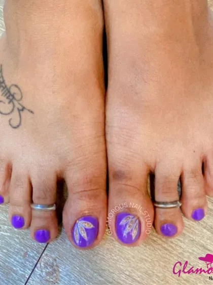 Your feet deserve to be pampered too. We offer complete pedicure services, including custom nail art. This look features a vibrant purple gel polish with a delicate, hand-painted leaf design on the big toes.