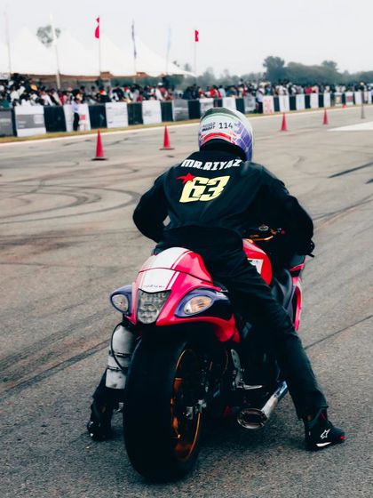 A rider on a Suzuki Hayabusa, with the name 'Mr. Riyaz' on his back, waits for his turn to race.