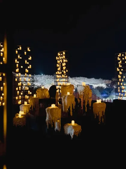 An artful installation of "melting" candles and towering candle grids set against the Jaisalmer night sky, creating a dramatic and unforgettable visual.