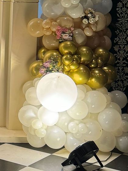 A cluster of white and gold balloons at the base of the backdrop, with a large illuminated orb that adds a magical glow to the setup.