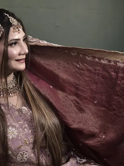 The bride playfully holding her dupatta. This shot captures the joy and excitement of the engagement ceremony.