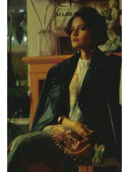 A portrait where the edgy leather jacket contrasts with the soft, traditional embroidery of the dress. This styling choice is central to the chapter's theme of conflicting emotions.