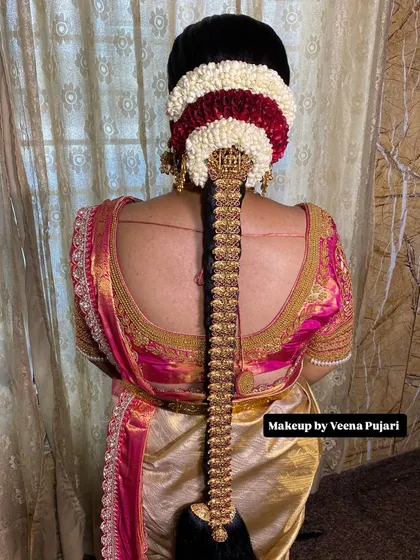 A South Indian bridal look is incomplete without the perfect hairstyle. This traditional Poola Jada, intricately woven with fresh jasmine, red flowers, and gold ornaments, is a classic choice that adds a divine touch of elegance and completes the bride's muhoortham attire.