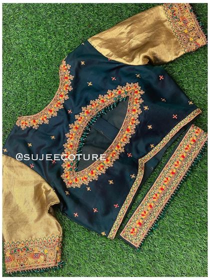 A dark green and gold blouse set laid flat. The blouse features a keyhole cutout at the back and is designed with contrasting gold sleeves and delicate orange and red embroidery.