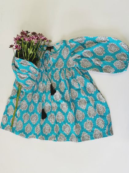 Dreamy cottons for the summer. This turquoise dress with a block print and tassel details is light, airy, and perfect for keeping cool while looking stylish.
