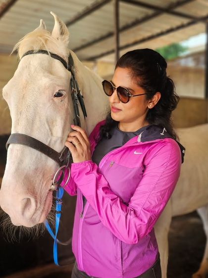 A rider posing with her beautiful white horse in the stable area. Our horses are not just for riding, they are companions.