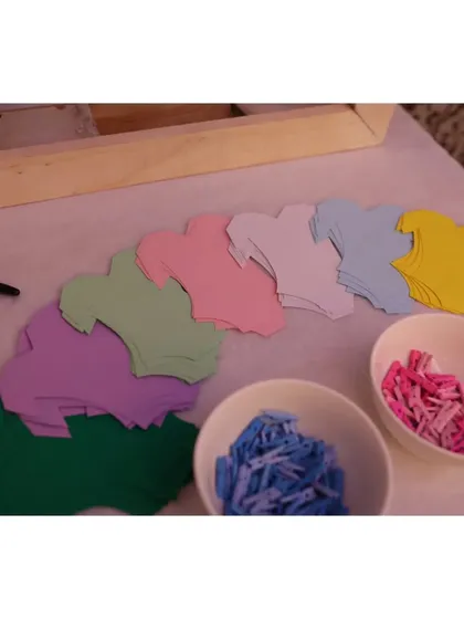 A "Wishes for the Baby" activity station, where guests could write messages on colorful onesie-shaped cards and hang them up for the parents-to-be.