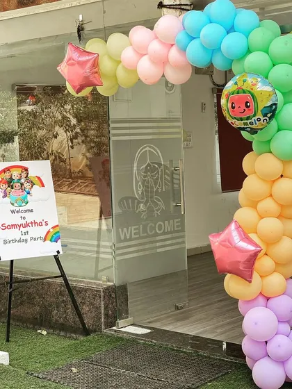 A simple yet cheerful Cocomelon-themed entrance decoration. A colorful balloon garland and a personalized welcome sign on an easel create a warm and inviting entry for party guests.