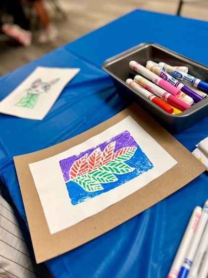 The final result of a multi-colored leaf print, sitting next to the markers used to create it.