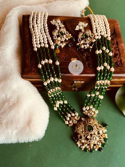 This emerald green and pearl long necklace is a statement piece. The layers of pearls and green beads create a beautiful contrast, perfect for festive wear.
