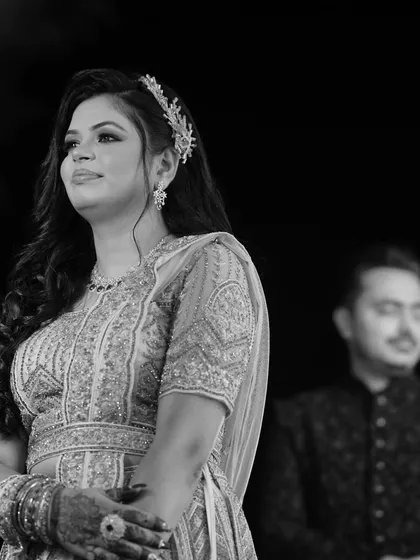 A black and white shot capturing the couple in a quiet moment. The groom is slightly out of focus in the background, drawing all attention to the bride's elegant profile.