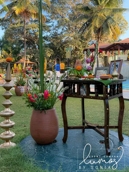 Another view of the traditional offerings table, set up in a garden with a backdrop of palm trees.