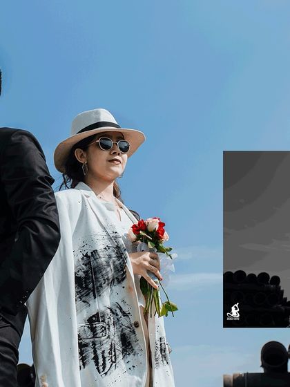 A striking pre-wedding photo with a bright blue sky contrasting with the couple's chic, dark and light outfits.