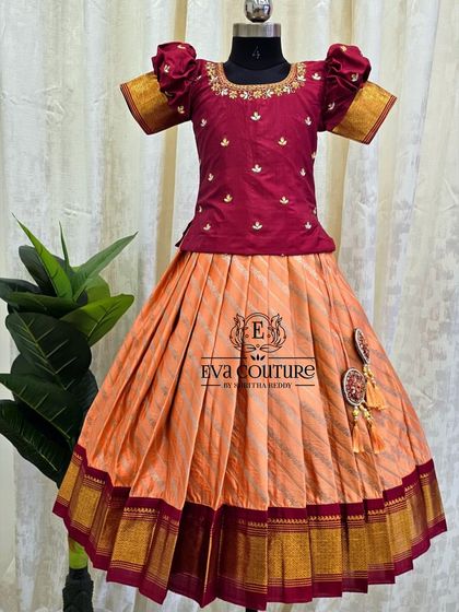 A lovely peach and maroon Pattu Pavadai. The striped skirt is paired with a beautifully embroidered blouse that has a keyhole back design.