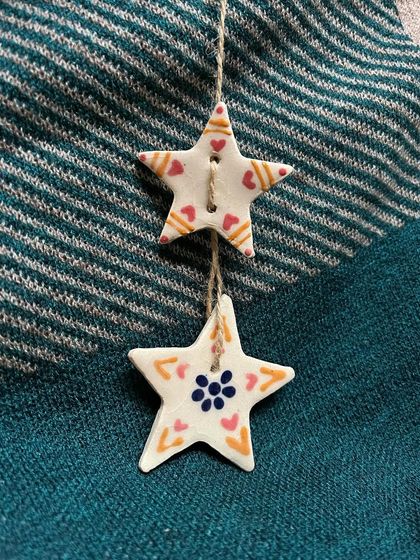A set of two star-shaped ornaments with hand-painted hearts and floral motifs.